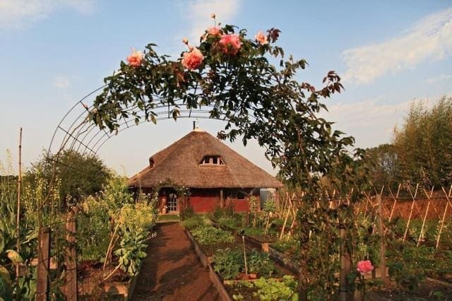Casa com um portal que leva à uma plantação com técnicas da permacultura