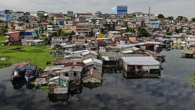 um bairro carente com casas simples e próiximo a locais alagados representa o problema do Racismo Ambiental