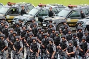 Foto representativa da Violência e segurança pública no Brasil, viaturas da polícia lado a lado e à frente vários soldados da polícia militar.