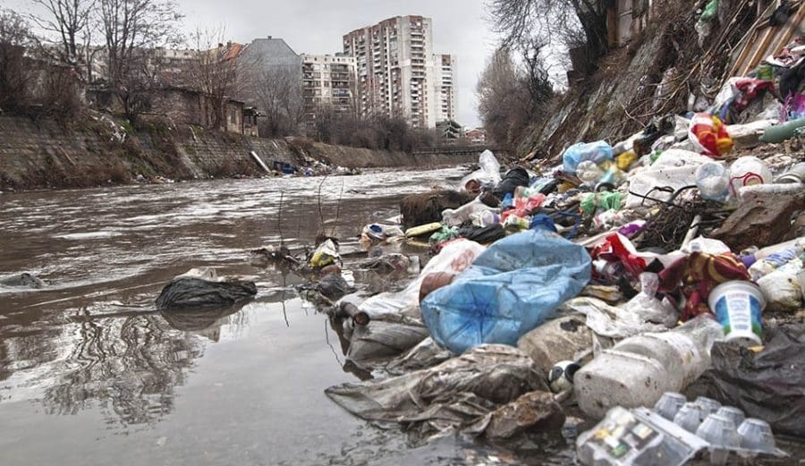 Muito lixo em um rio perto de uma cidade evidencia a poluição ambiental